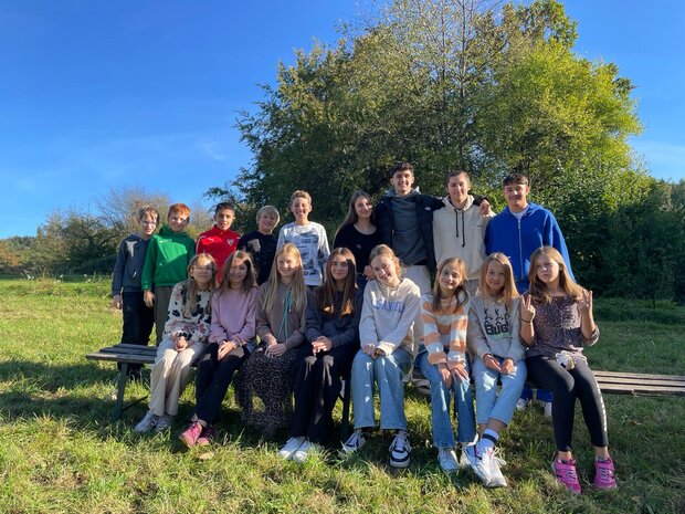 Eine Gruppe von Schüler*innen, die für ein Foto auf einer Bank sitzen oder stehen.