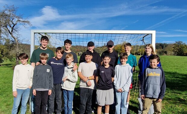 Eine Gruppe von Schüler*innen, die für ein Foto vor einem Fußballtor  stehen.