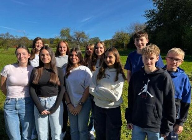 Eine Gruppe von Schüler*innen auf einer Wiese.