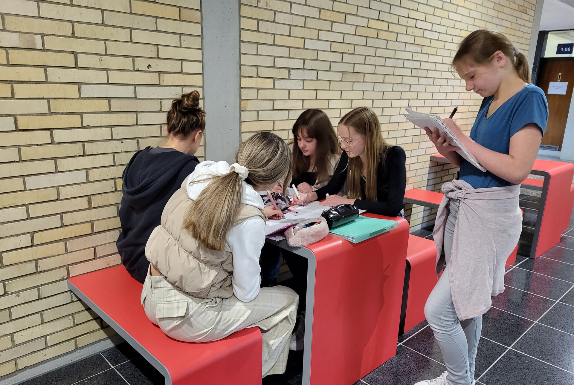 Foto von 5 Mädchen, die aneinem Tisch zusammen arbeiten.