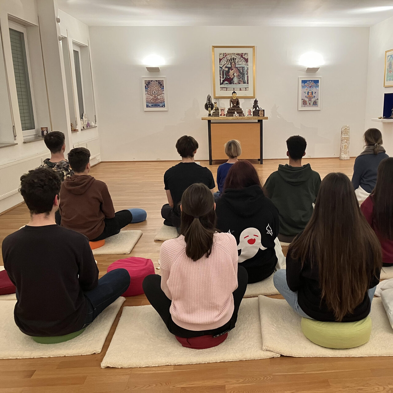 Foto einer sitzenden Gruppe von Schülerinnen und Schülern, beim Besuch des Buddhistischen Zentrums in Stuttgart.