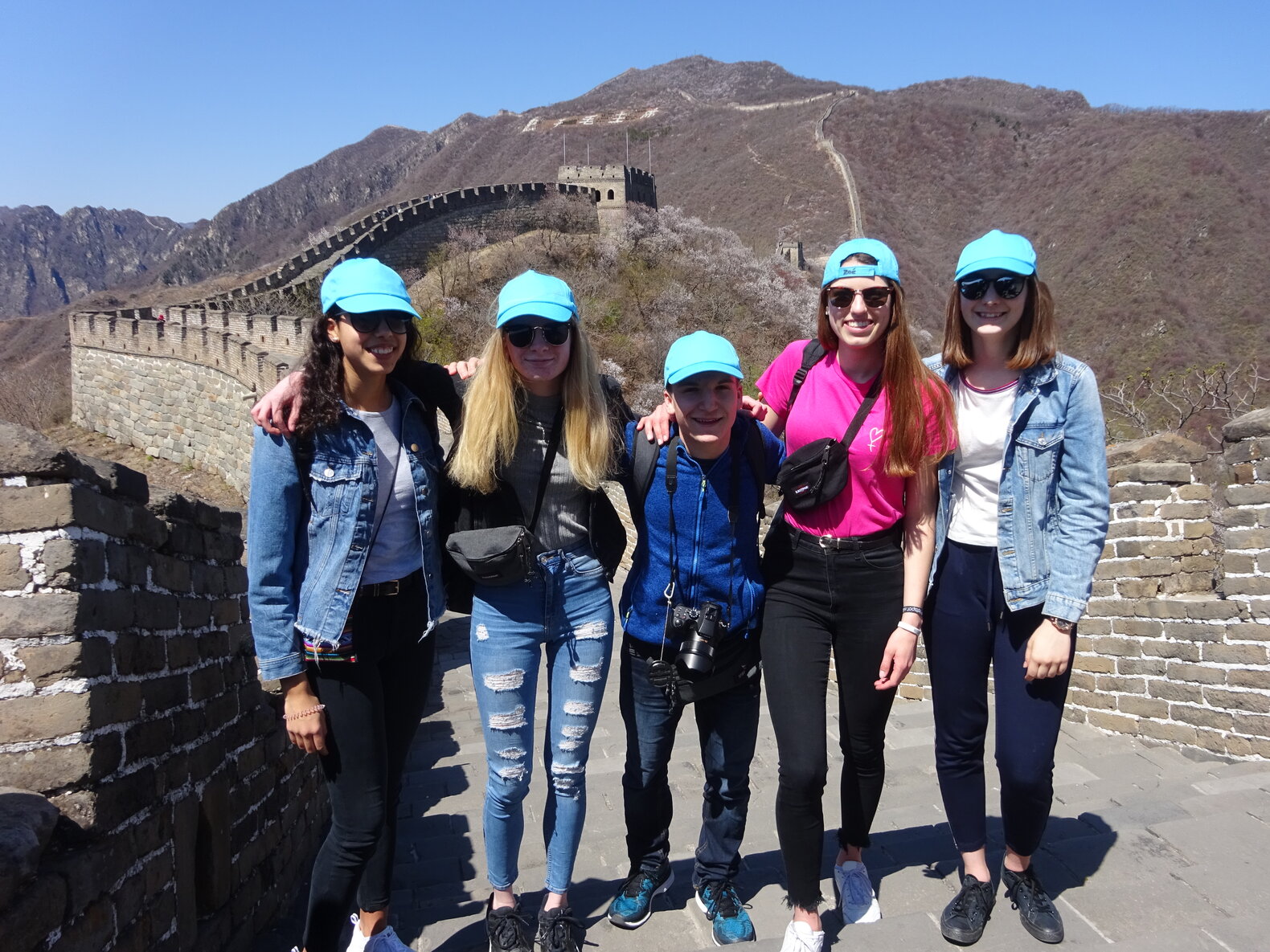 Fünf Schüler*innen, die auf der Chinesischen Mauer stehen.