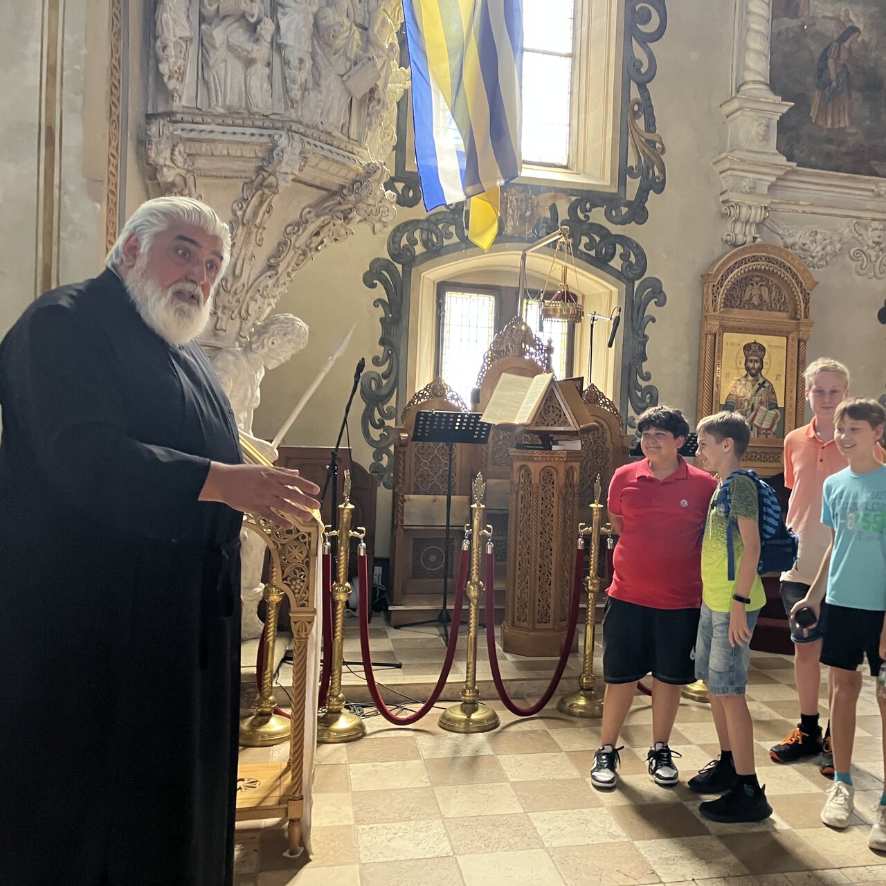 Foto einer Gruppe von Schülerinnen und Schülern, die vor einem Pastor in einer Kirsche stehen und etwas erklärt bekommen.